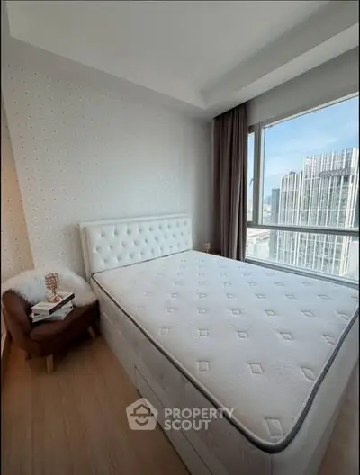 Modern bedroom with large window and city view, featuring a comfortable bed and stylish decor.