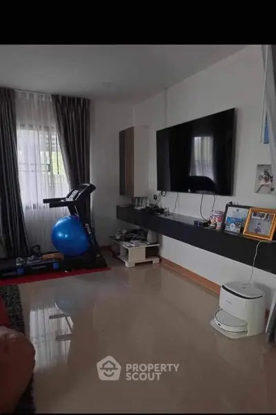 Modern living room with exercise equipment and wall-mounted TV, perfect for fitness enthusiasts.