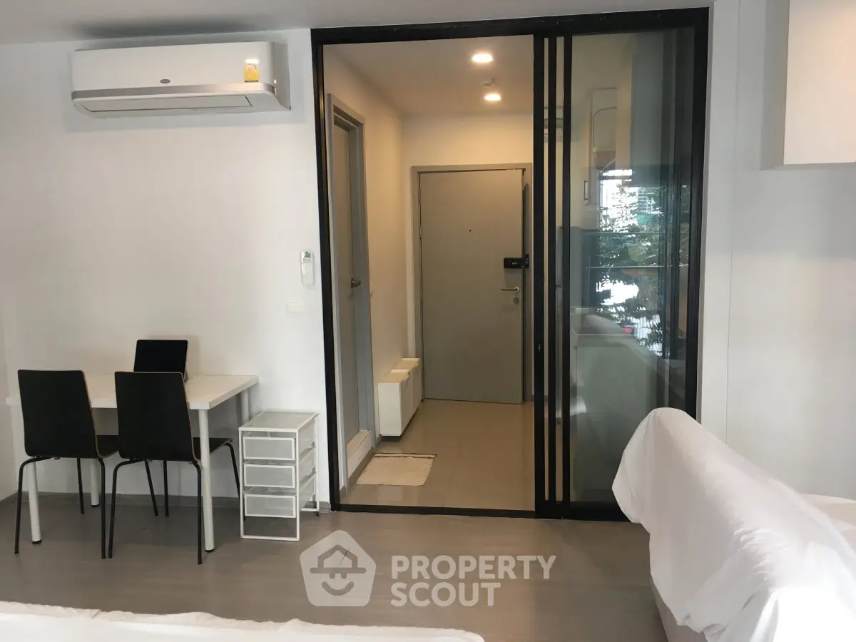 Modern apartment interior with sleek furniture and air conditioning, featuring a sliding glass door and cozy dining area.