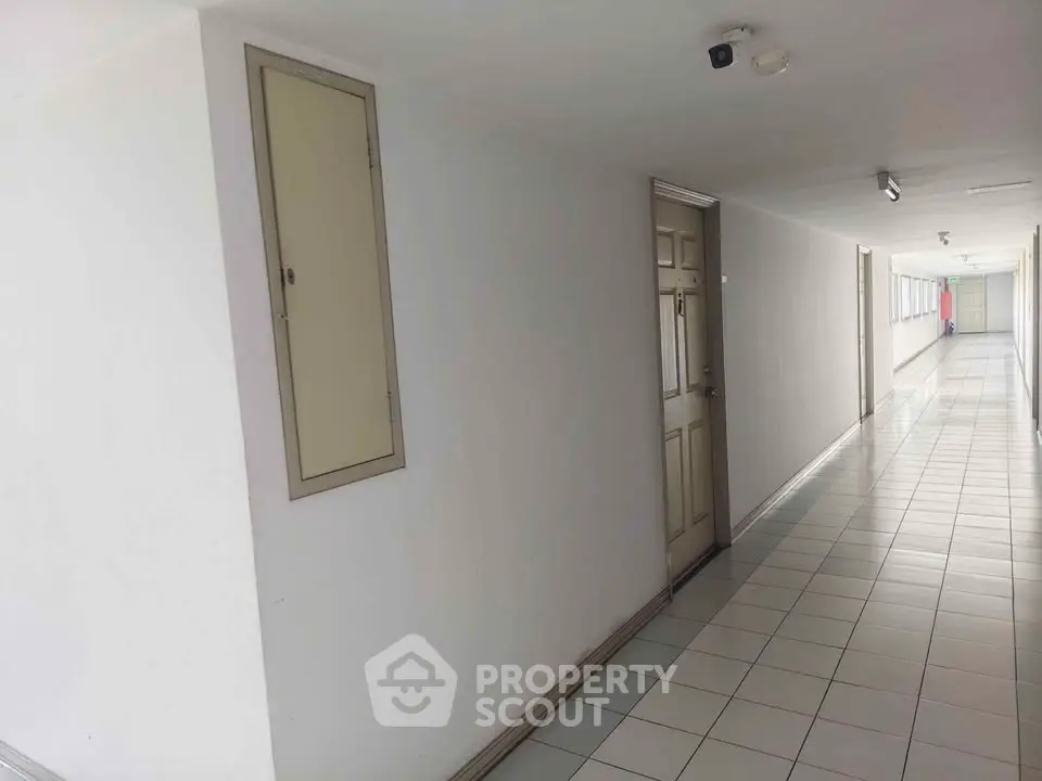 Spacious corridor with tiled flooring and multiple doors in a residential building.