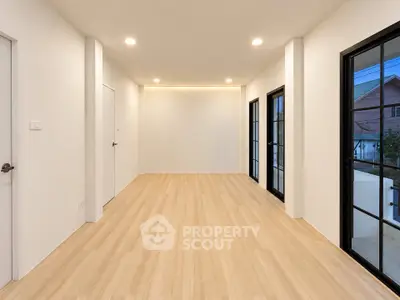 Spacious modern room with wooden flooring and large windows