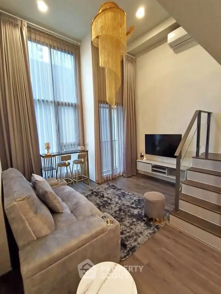 Modern living room with high ceilings, elegant chandelier, and stylish furniture in a duplex apartment.