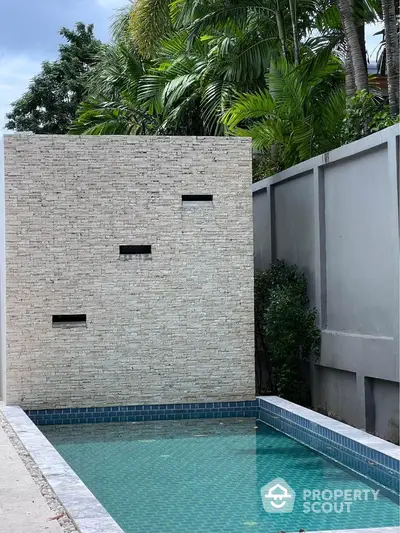 Luxurious private pool with modern stone wall and lush greenery