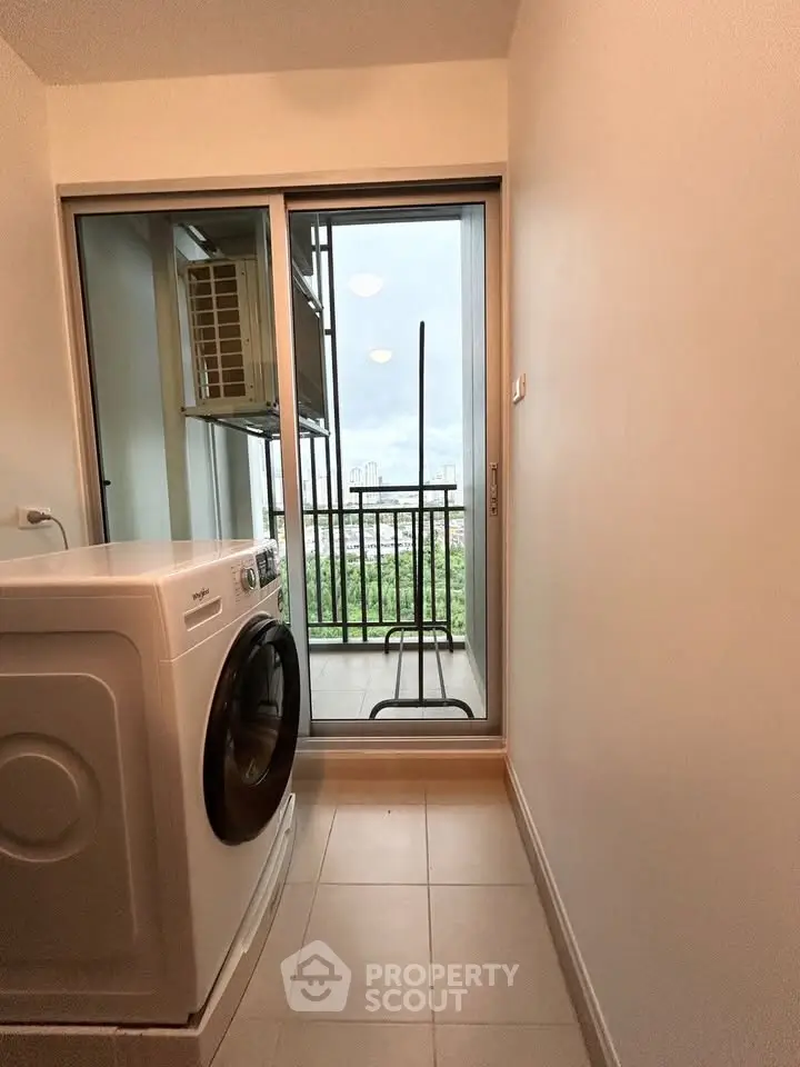 Compact laundry area with washing machine and balcony view in modern apartment.
