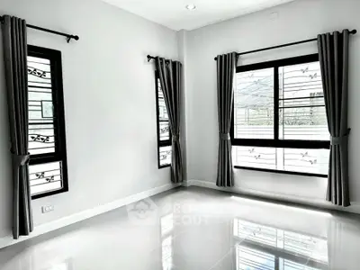 Spacious empty room with large windows and elegant curtains, perfect for customization.