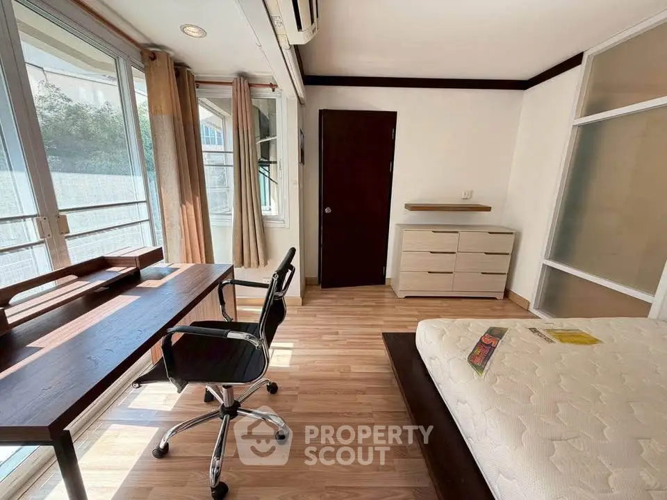 Bright bedroom with study area, large windows, and modern furnishings in a stylish apartment.