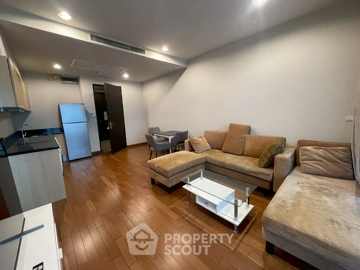 Modern living room with cozy sectional sofa and open kitchen layout in stylish apartment.