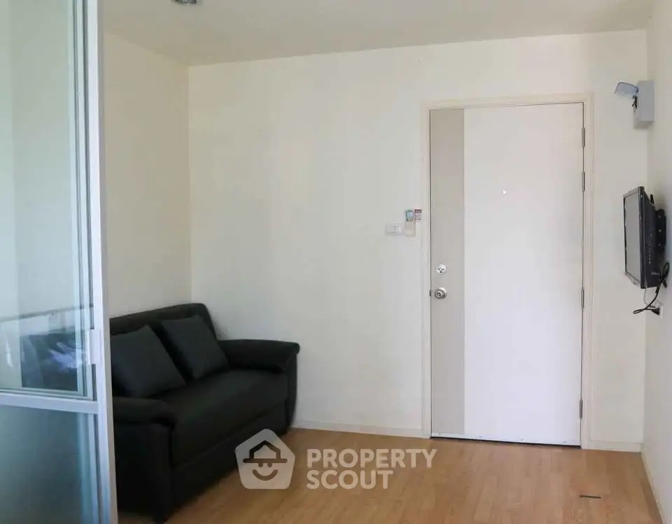 Cozy living room with modern sofa and wall-mounted TV, featuring sleek wooden flooring and a minimalist design.