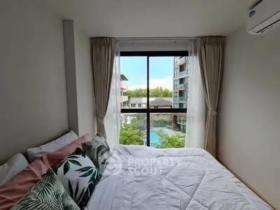 Cozy bedroom with large window offering a stunning pool view in modern apartment.