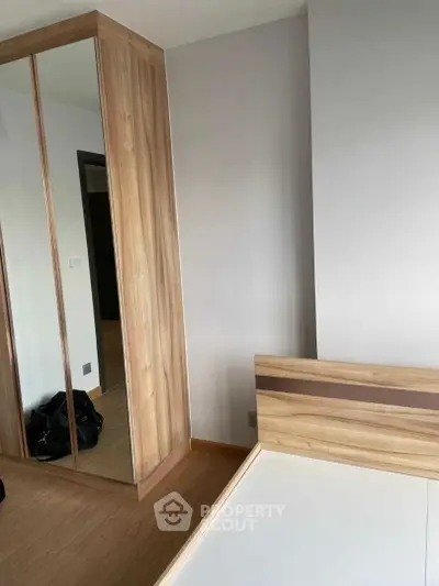 Modern bedroom with wooden wardrobe and bed frame, showcasing minimalist design.