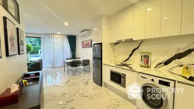 Modern kitchen with marble flooring, sleek appliances, and open layout leading to dining area.