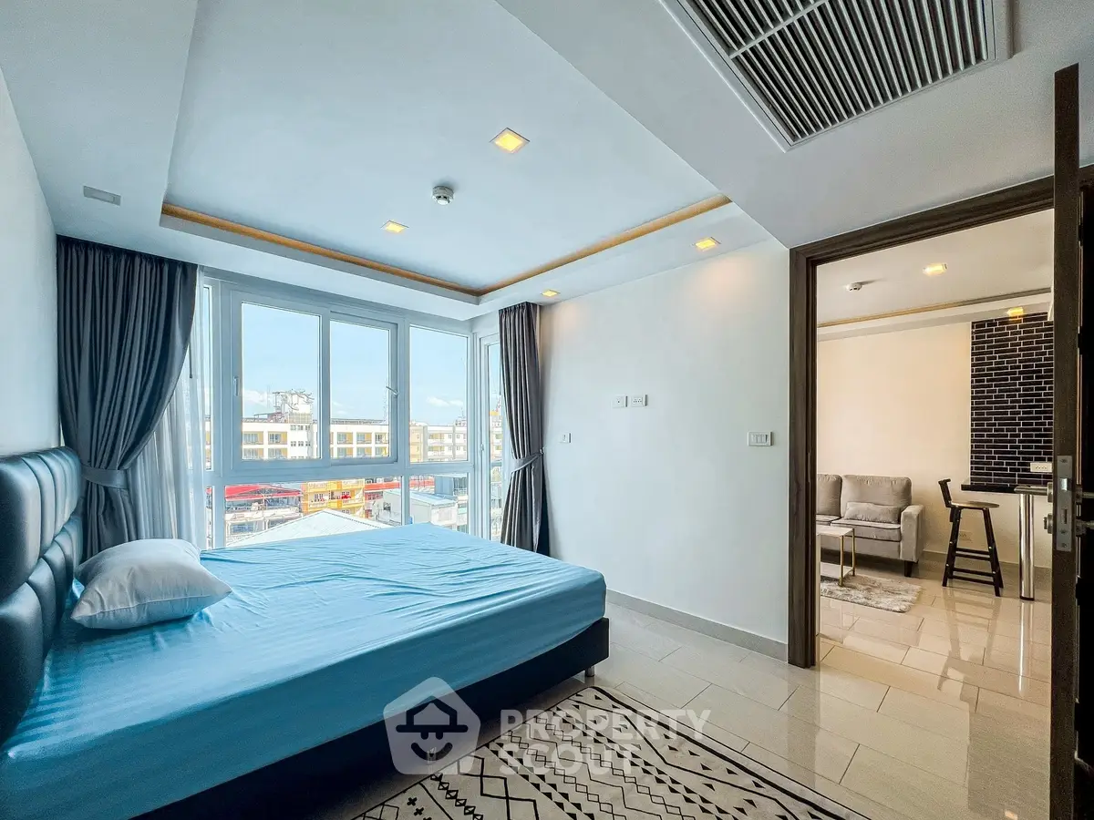Spacious bedroom with large windows and modern decor, offering a bright and airy atmosphere.