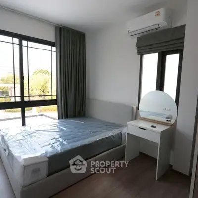 Modern bedroom with large window and air conditioning, featuring a stylish vanity.