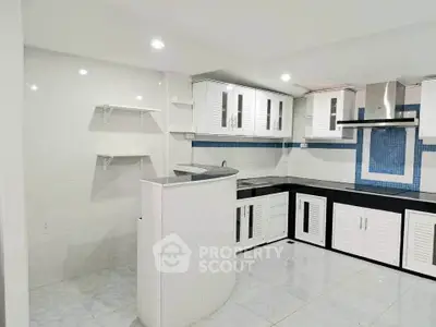 Modern kitchen with sleek white cabinets and black countertops in a stylish open layout.