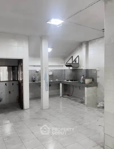 Spacious kitchen with tiled flooring and open layout, featuring modern appliances and ample counter space.