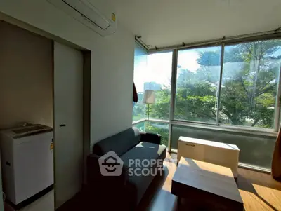 Cozy living room with large windows and scenic view of greenery