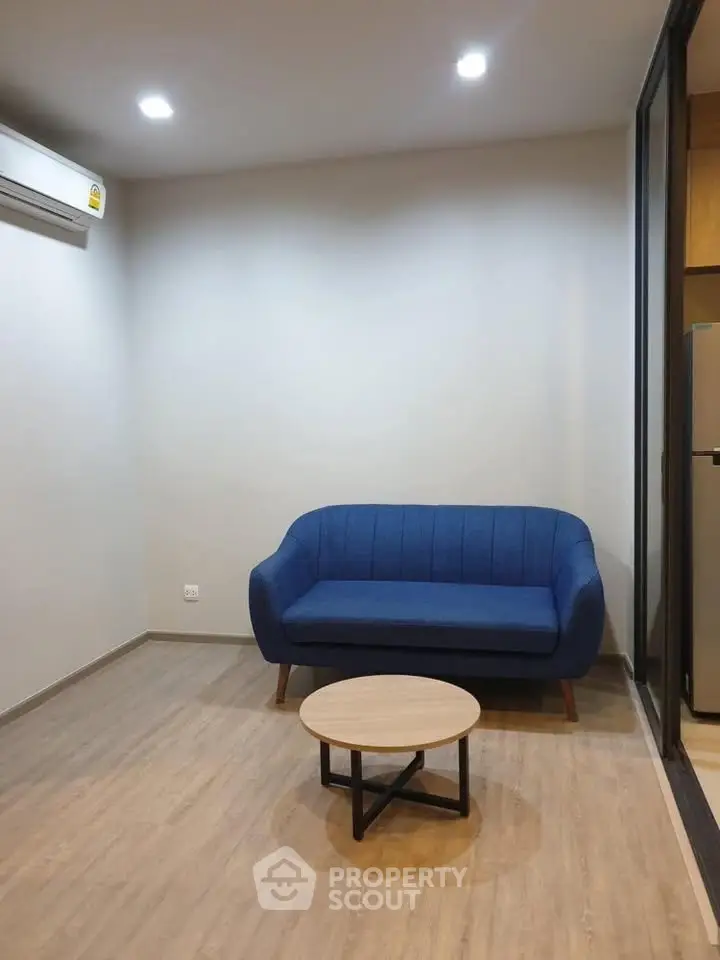 Modern living room with blue sofa and wooden coffee table, featuring minimalist design and cozy ambiance.