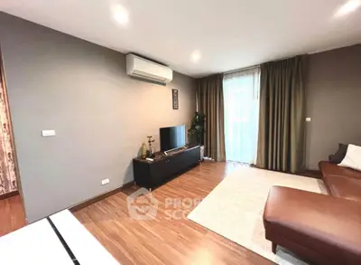 Spacious living room with modern decor and natural light, featuring a sleek air conditioning unit and cozy seating.