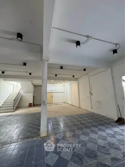 Spacious interior with tiled flooring and staircase, ideal for versatile use.