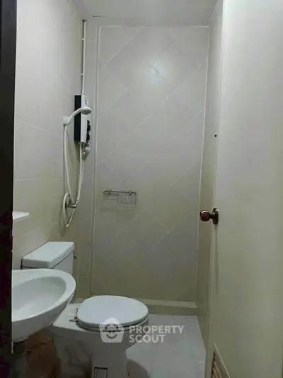 Compact bathroom with toilet, sink, and shower in minimalist design.