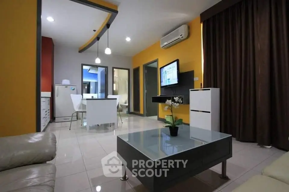 Modern living room with sleek furniture and open kitchen layout, featuring bright yellow walls and stylish decor.