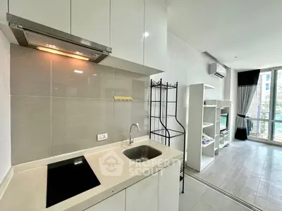 Modern open-layout kitchen with sleek design and adjacent living area, featuring large windows for natural light.