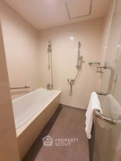 Modern bathroom with sleek bathtub and dual shower heads in a contemporary apartment.