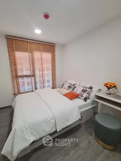 Cozy bedroom with modern decor and natural light, featuring stylish blinds and elegant furnishings.