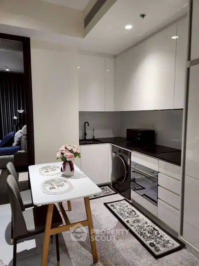 Modern kitchen with sleek white cabinets, integrated appliances, and stylish dining area.
