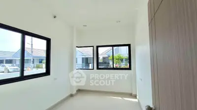 Bright room with large windows offering a view of modern houses, ideal for a cozy study or office space.