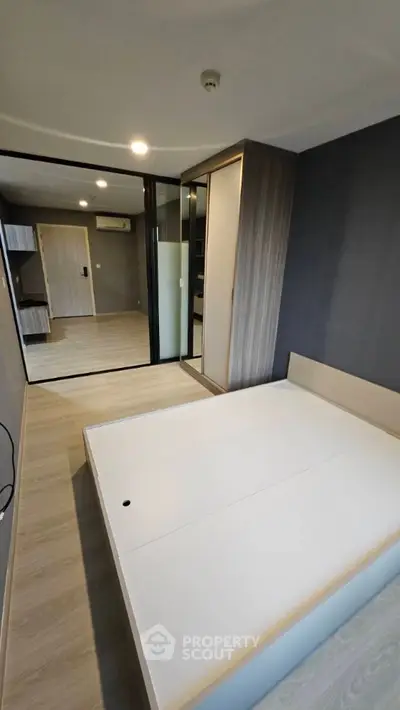 Modern bedroom with sleek design and mirrored wardrobe in a stylish apartment.
