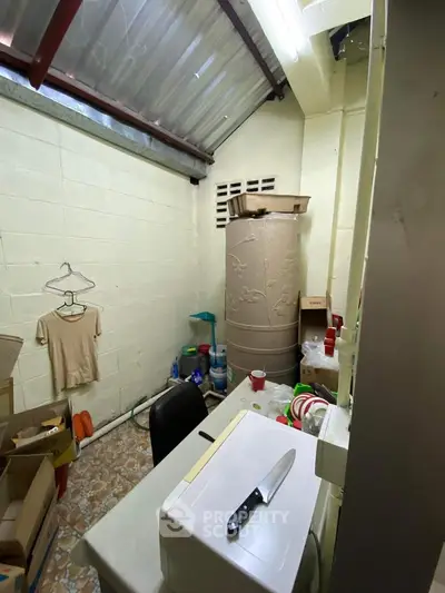 Compact storage room with washing machine and household items, ideal for organizing essentials.