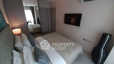 Cozy bedroom with modern decor, wall-mounted TV, and mirrored closet doors, perfect for relaxation.