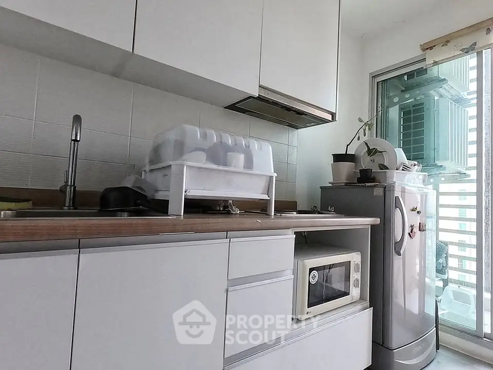 Modern kitchen with sleek cabinets and appliances, featuring a microwave and refrigerator.