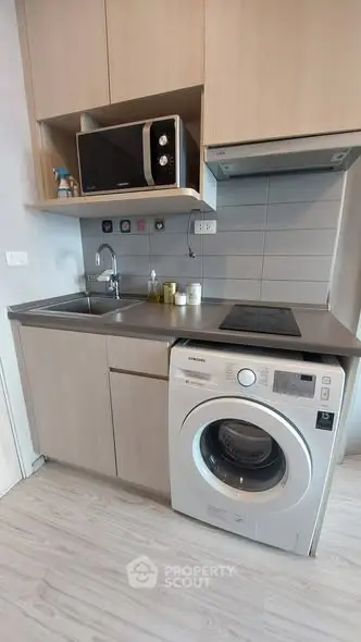 Modern compact kitchen with washing machine and microwave in sleek apartment