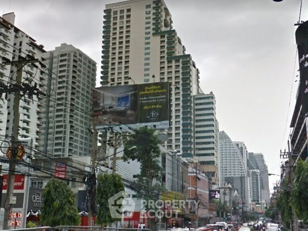 Urban street view with high-rise buildings and commercial establishments.