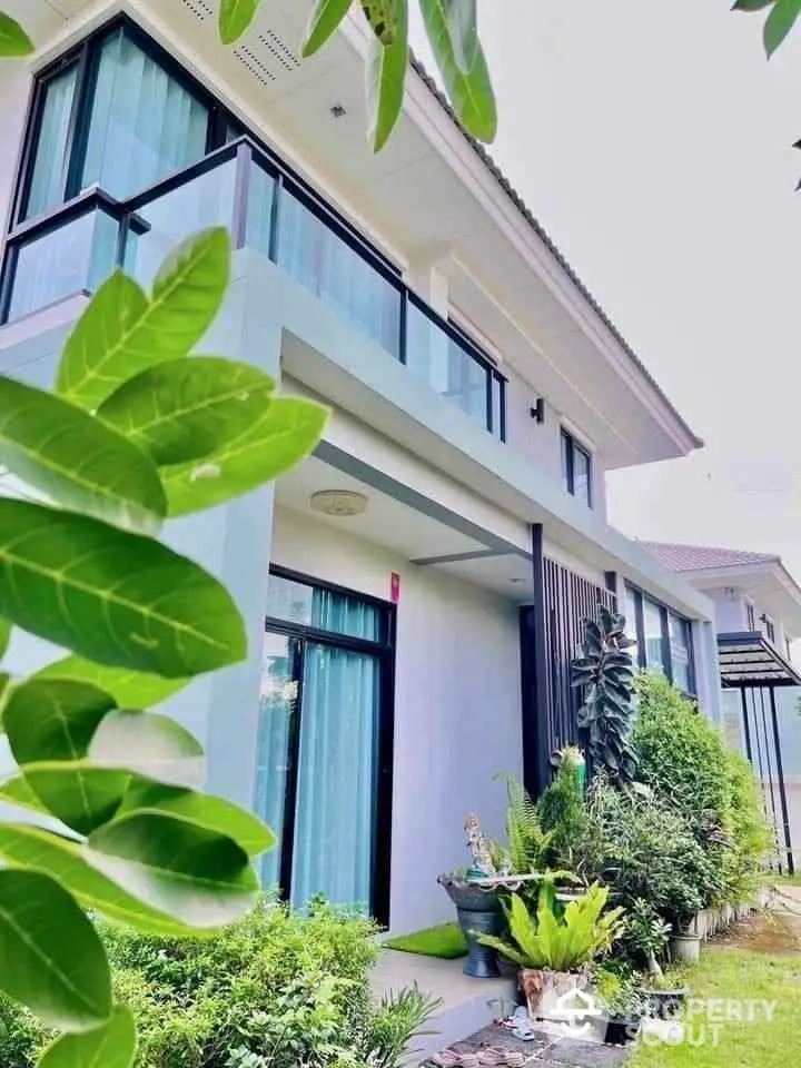 Modern two-story house with lush garden and balcony, perfect for serene living.