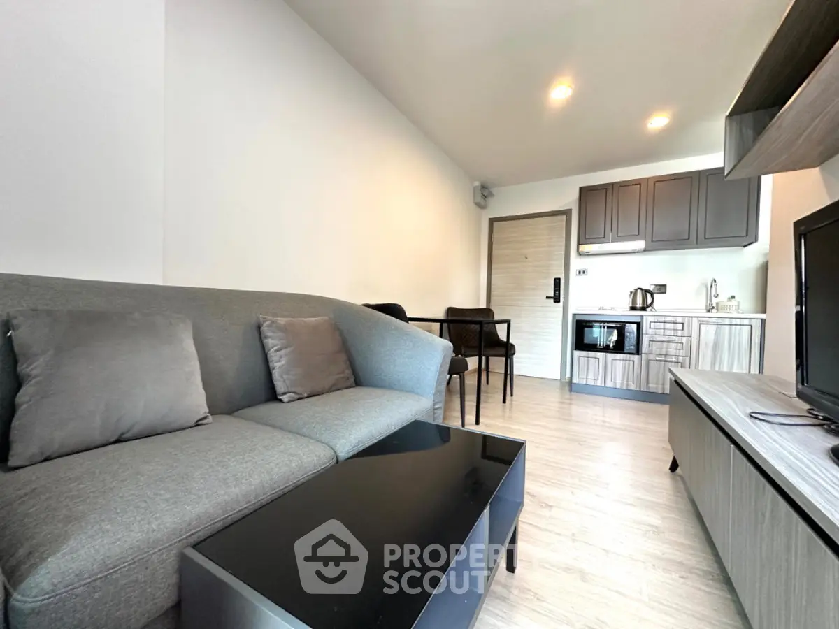 Modern living room with sleek furniture and open kitchen layout in a stylish apartment.