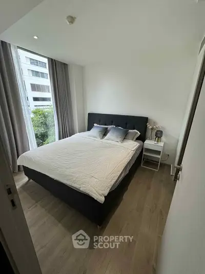 Modern bedroom with large window and stylish decor in urban apartment