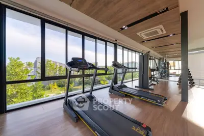 Modern gym with large windows offering a scenic view, equipped with treadmills and fitness machines.