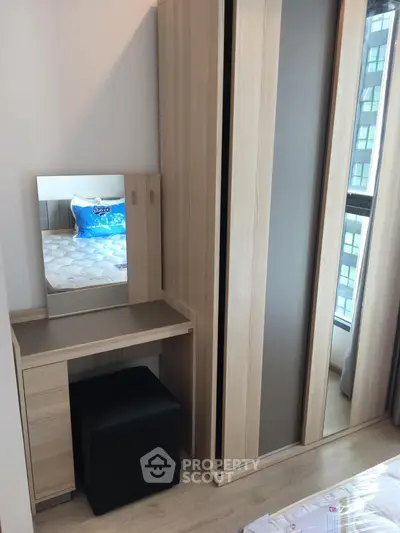 Modern bedroom with sleek wardrobe and vanity set, featuring a large window for natural light.