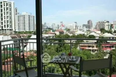 Stunning cityscape view from a cozy balcony with seating area, perfect for relaxation.