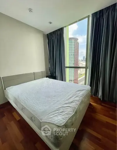 Modern bedroom with large window offering stunning city view and natural light.