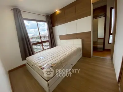 Modern bedroom with large window and wooden flooring, featuring a comfortable bed and built-in wardrobe.