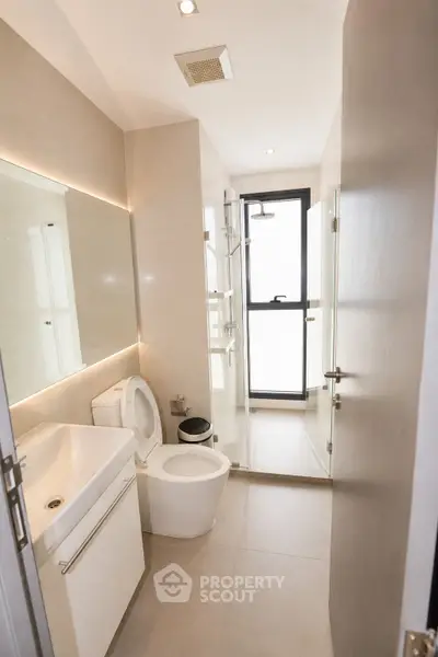 Modern bathroom with sleek fixtures and glass shower enclosure in contemporary apartment.
