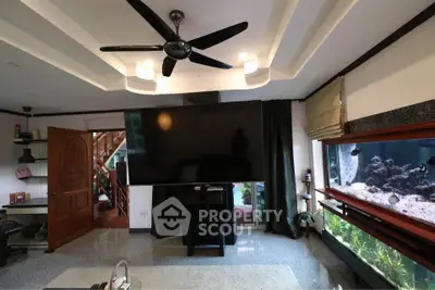 Spacious living room with large TV and aquarium, featuring modern ceiling fan and open layout.