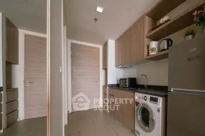 Modern kitchen with sleek cabinetry, washing machine, and stainless steel appliances in a compact layout.