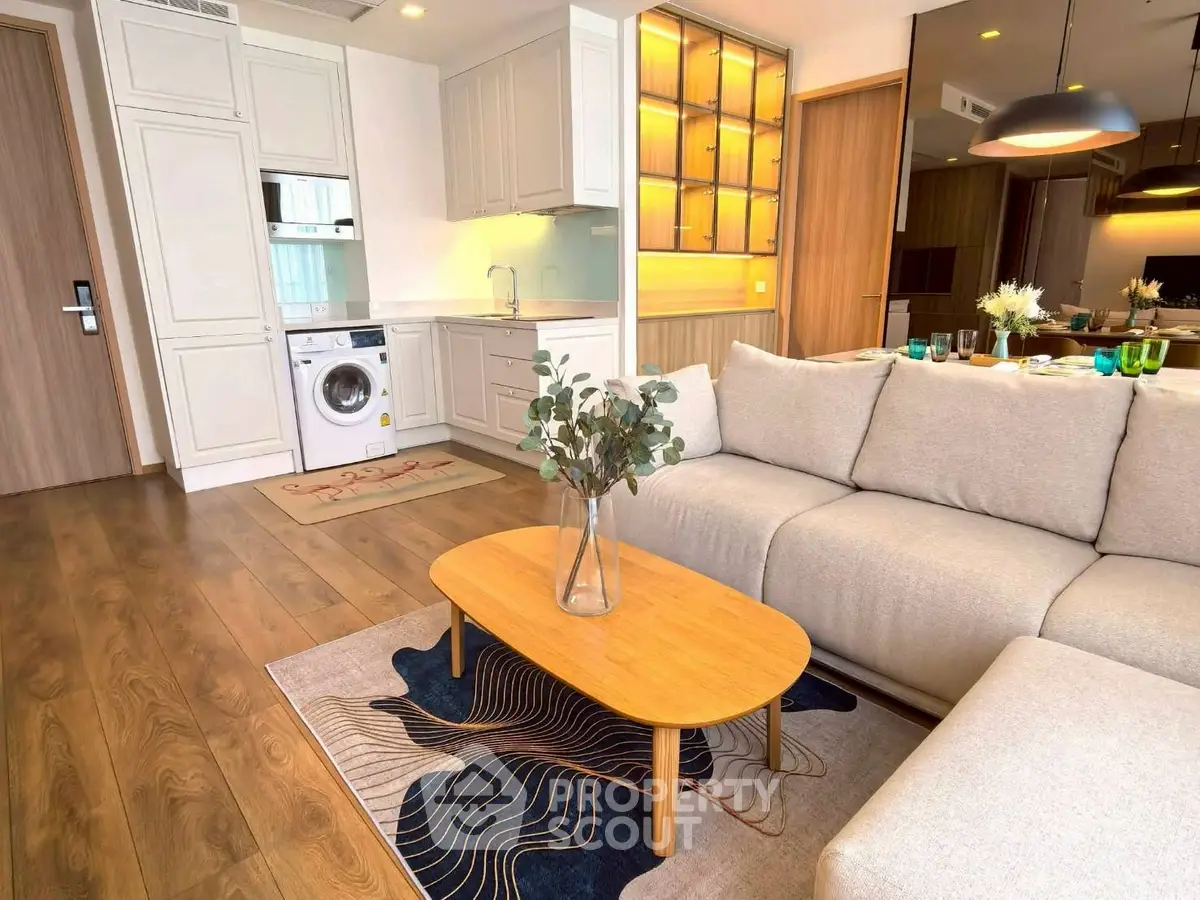 Modern living room with cozy sofa and stylish kitchen featuring washing machine.
