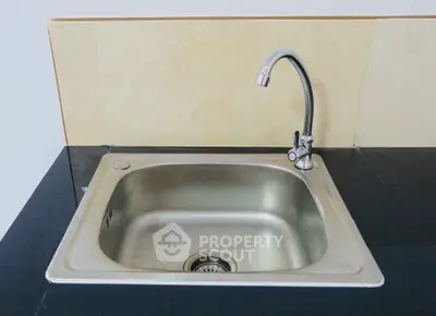 Modern kitchen sink with sleek faucet on black countertop