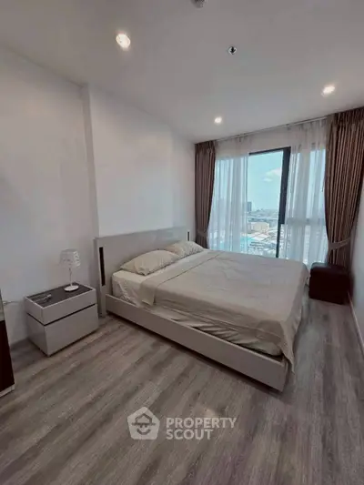 Modern bedroom with city view, featuring sleek design and ample natural light.